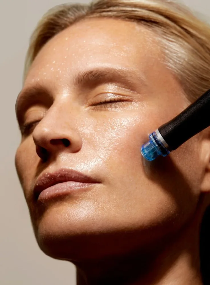 A client receiving a HydraFacial Glow treatment with a machine that hydrates and rejuvenates the skin.