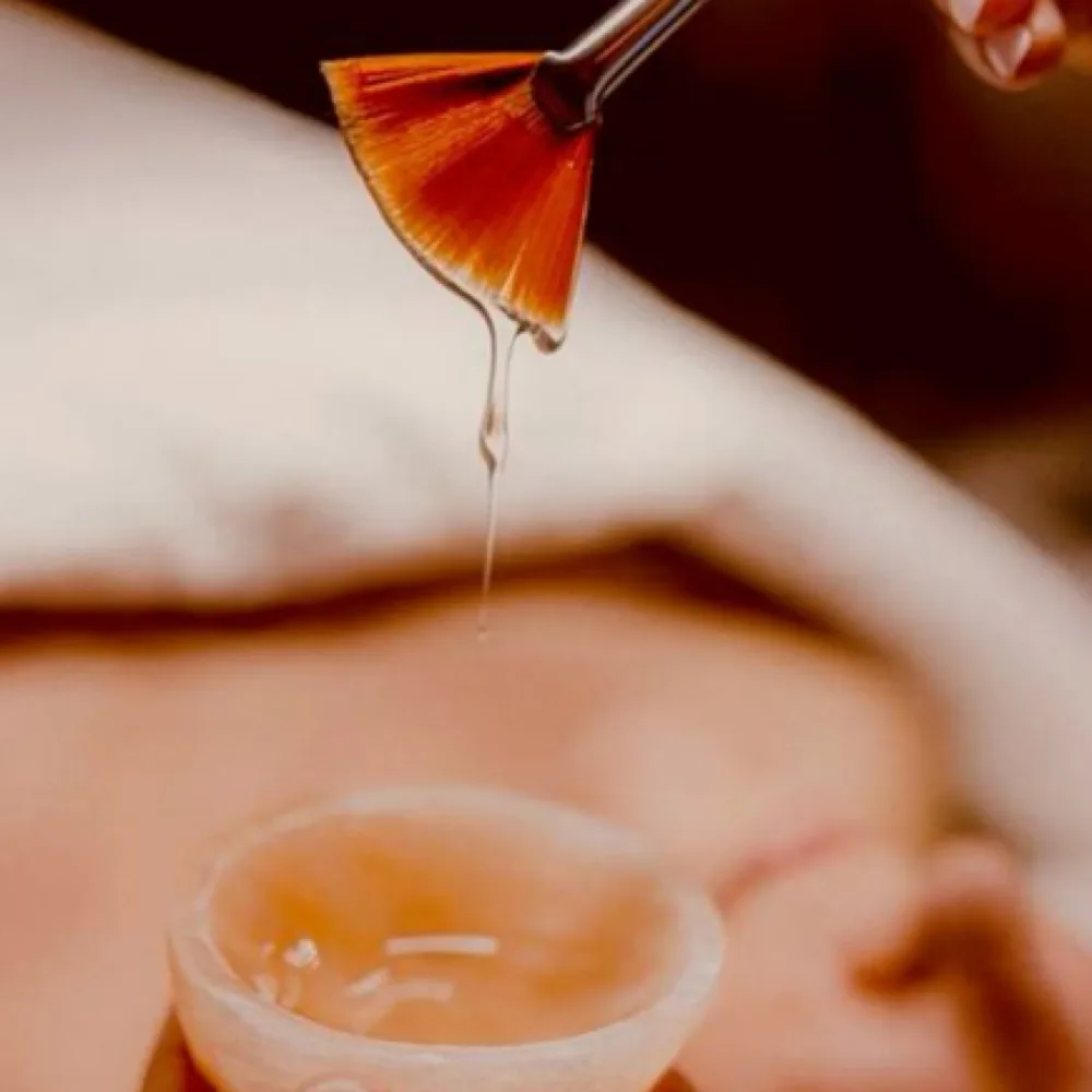 A technician applying a customized chemical peel treatment with a brush for skin rejuvenation.