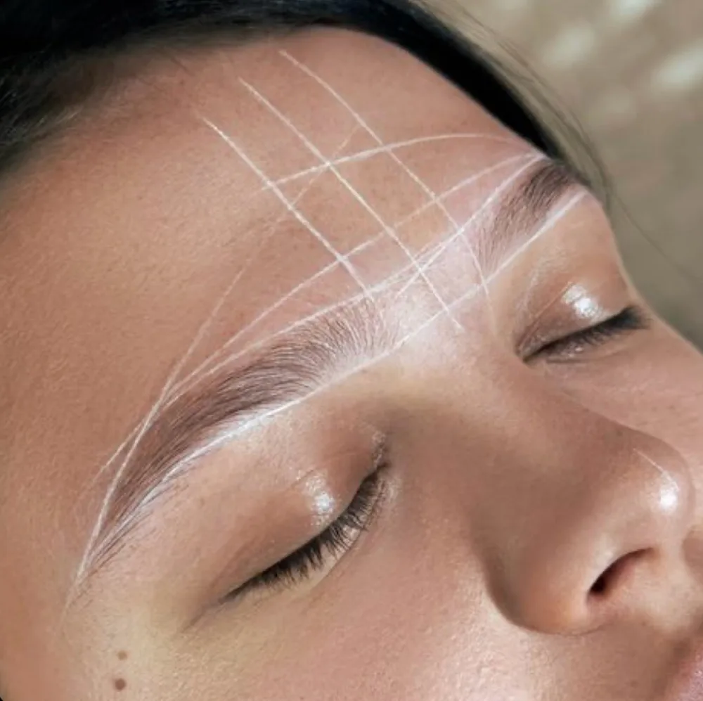 A client with marked guidelines for shaping their brows during an Eyebrow Wax Add On service.