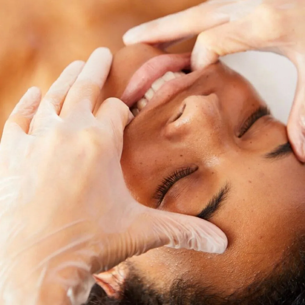 A practitioner performing a Buccal Massage Add On to relieve jaw tension and enhance facial contour.